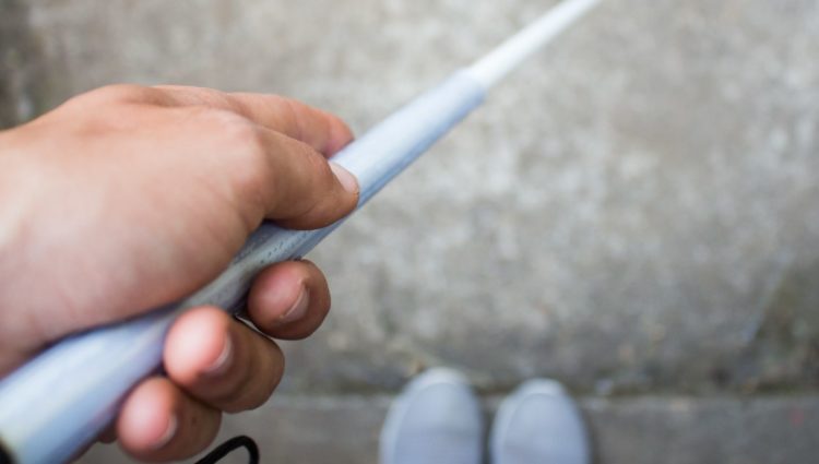 close up of hand holding white cane