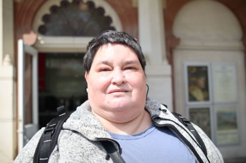 Iris Keppler headshot. Iris is wearing a white t-shirt and beige coat and is smiling at the camera.