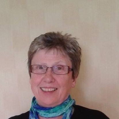 Headshot of Lesley Robinson, North Yorkshire SLC member. Lesley is standing against a cream wall. She has short hair and is wearing glasses. She is smiling at the camera.