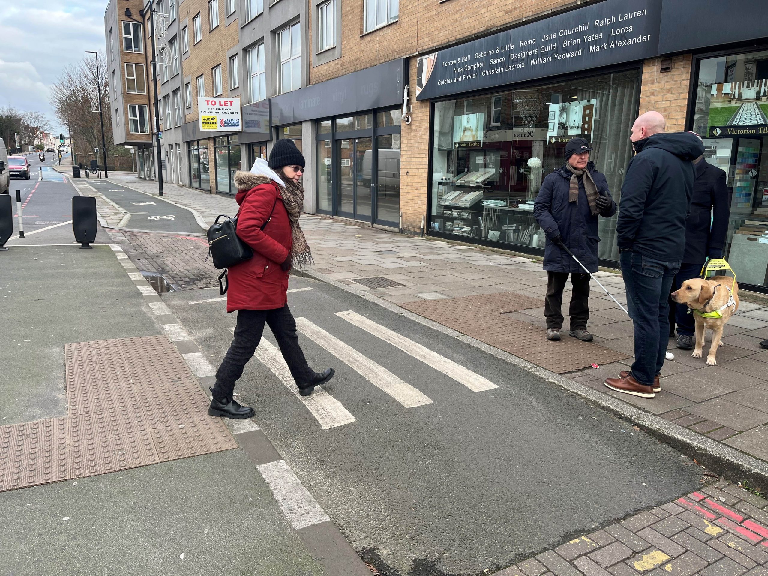 Vicky, South West London SLC volunteer, crossing a zebra crossing on a 'floating bus stop'. Fellow SW London volunteer, Harry is pictured on the path alongside a representative from Wandsworth Council.