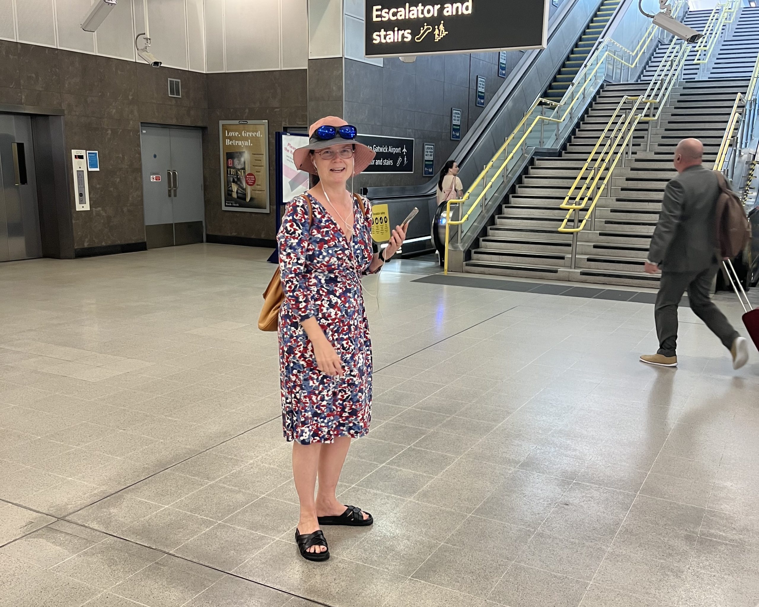 Vicky Blencowe, South West London SLC member, pictured at London Blackfriars train station. She is facing the camera, and holding her smartphone in her hand, whilst on the phone to an AIRA representative.