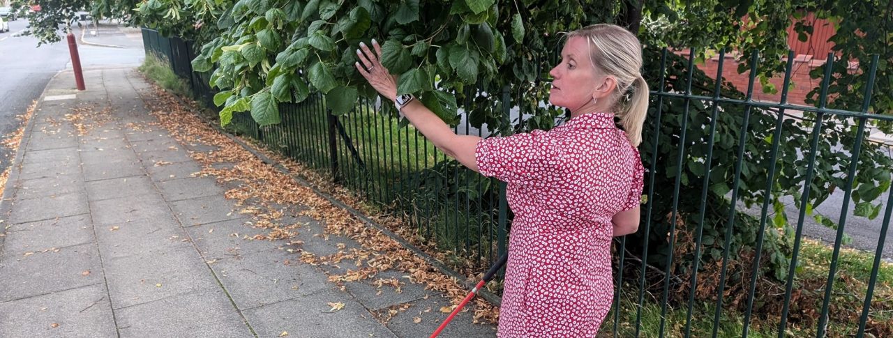 Sight Loss Council Engagement Manager, Kelly, who is registered blind, walks into an overgrown and overhanging tree whilst walking down the pavement.