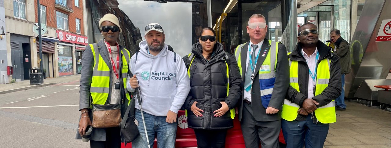 Steve Reed in front of a red bus with four TFL bus drivers and trainers at London SLC's Meet The Bus event