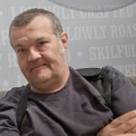 Headshot of Toby Morgan smiling at the camera and wearing a dark grey t-shirt.