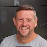 Kevin Crompton headshot. Kevin is wearing a grey t-shirt and short brown hair. He is smiling at the camera.