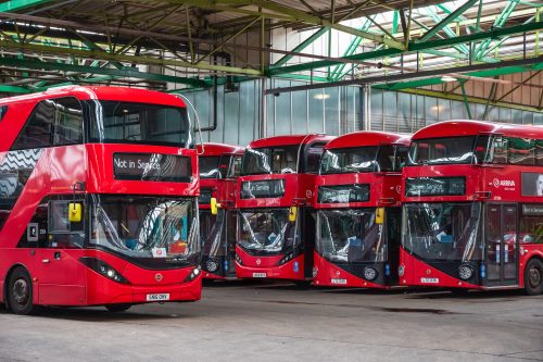 Row of four red double-decker buses parked in a line.